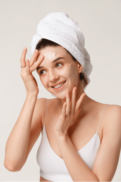 Woman cleansing and applying moisturizer to her face before starting simple party makeup